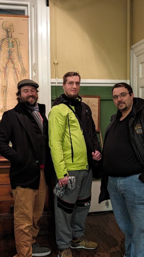 Three of us in winter coats in an old building with an anatomy chart on the wall