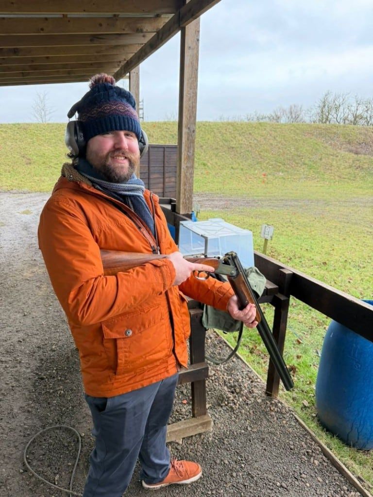 Holding a broken-open shotgun at a clay pigeon shooting ground on a winter day